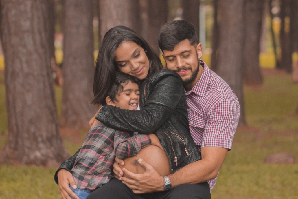 A family portrait. A child who appears to be preschool age hugs his mother's pregnant belly.