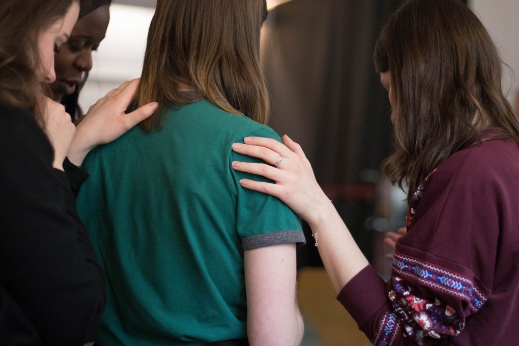Women place their hands on another woman's shoulder