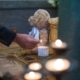 A person lights a candle near a child's teddy bear