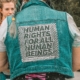 A woman wearing a denim vest with a human rights message on it