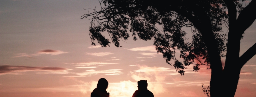 Silhouettes sitting in front of a sunset