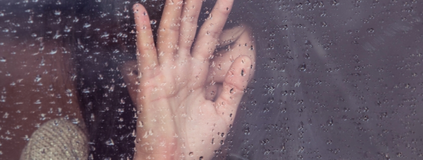 A grieving woman behind a window