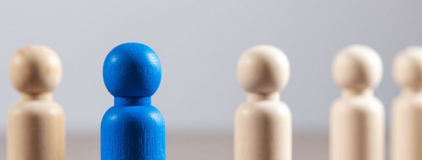 Blue Wooden Figure Standing Out From Crowd
